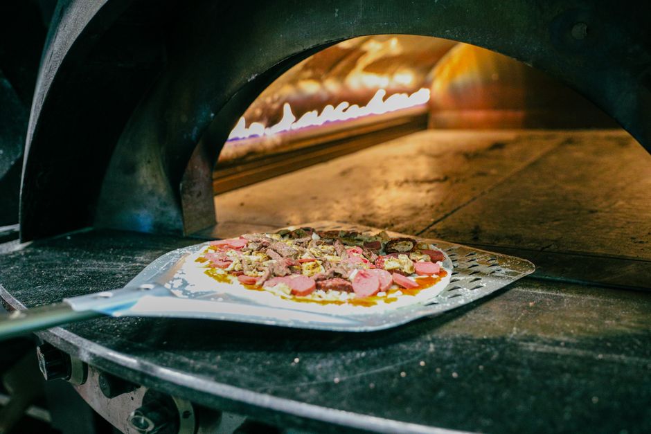 Hands actively kneading pizza dough on floured work surface